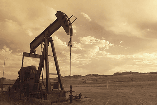 Oil rig in large field, sepia toned