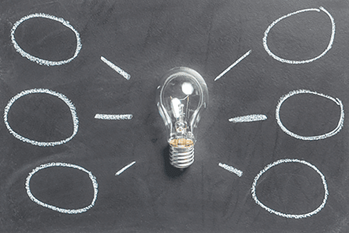 Lightbulb on a blackboard with chalk circles drawn around it.