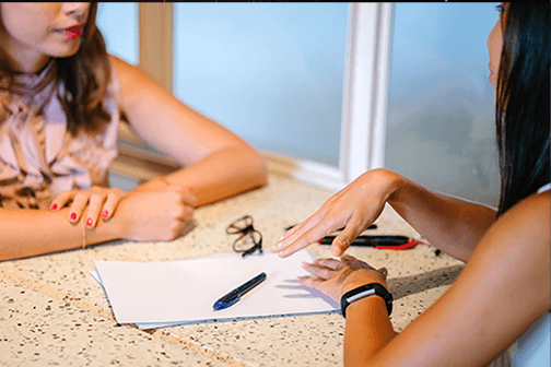 Two women chatting over a piece of paper