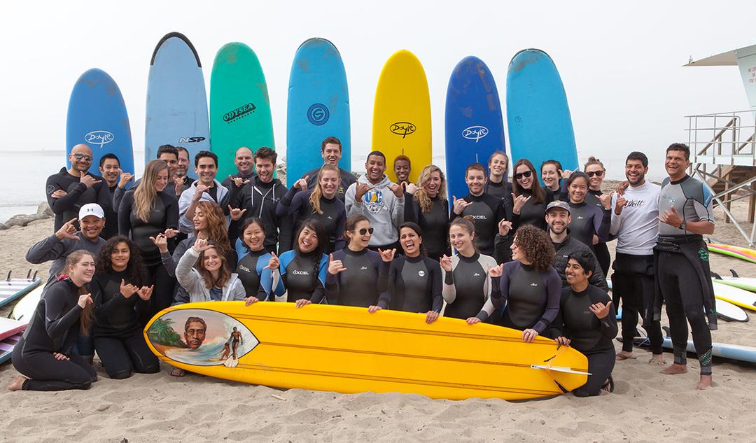 employees posing for a group shot with surfboards