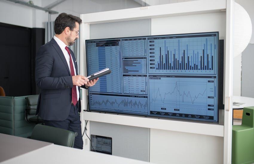 man looking at graphs on a big screen