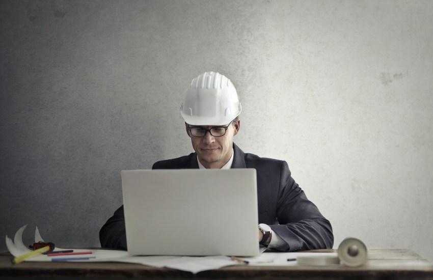 Man in a hardhat working on a laptop
