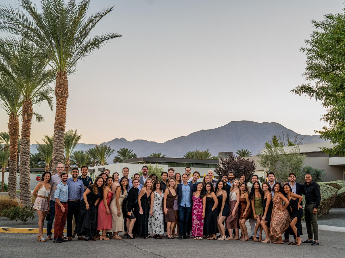 Decibio employees posing for a group shot in front of palm trees and mountains
